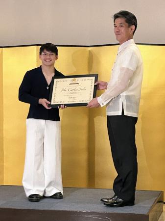 １日、マニラの日本大使公邸で、遠藤和也大使（右）から大使特別賞を受けるカルロスエドリエル・ユーロ選手（共同）