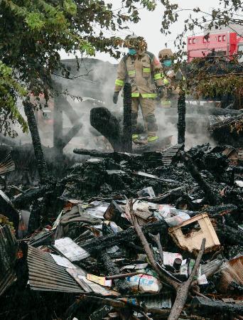 全焼した住宅を調べる消防関係者＝７日午前１１時、島根県出雲市