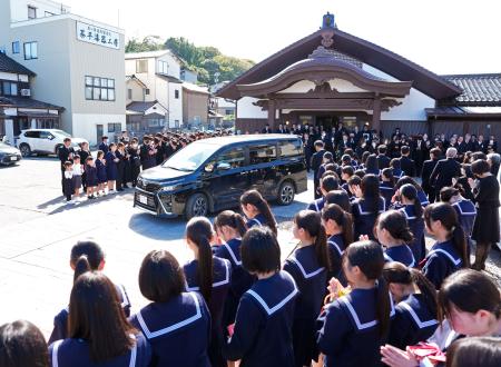 　喜三翼音さんの父鷹也さんらを乗せ、葬儀会場を出る車を見送る多くの参列者＝１２日午前、石川県輪島市