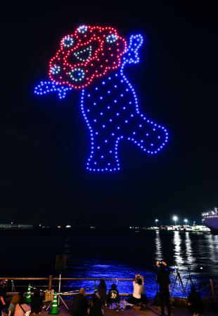 万博会場の大阪市の夢洲近くで開催されたドローンショーで、夜空に浮かび上がる公式キャラクター「ミャクミャク」＝１２日夜