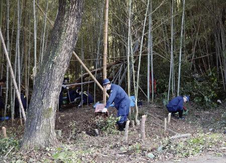 遺体が発見された雑木林を調べる捜査員＝５月、三重県四日市市