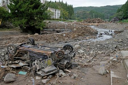 記録的豪雨で氾濫した塚田川沿いで、ひっくり返ったまま残る車＝２０日午前、石川県輪島市久手川町