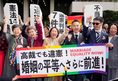 同性婚を巡る東京第１次訴訟の控訴審判決を受け、「高裁でも違憲」などと書かれた横断幕を掲げる原告ら＝３０日午前、東京高裁前