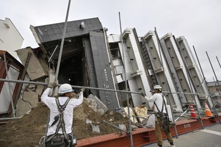 能登半島地震で倒壊し、１０カ月となった現在も横倒しのままとなっている石川県輪島市のビル。公費解体に向けた準備が始まった＝１日午後