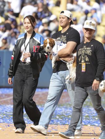 　ドジャースタジアムで行われた優勝報告会を終え、愛犬デコピンを抱いて引き揚げる米大リーグ、ドジャースの大谷翔平。左は妻の真美子さん＝１日、ロサンゼルス（共同）