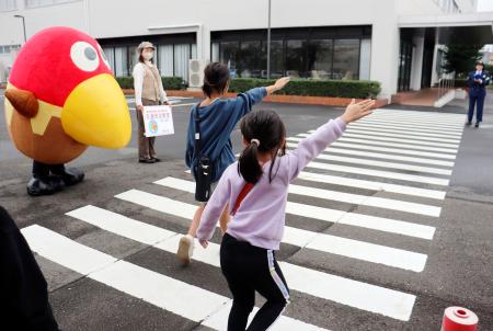 人気キャラクター「キョロちゃん」（左）が見守る中、横断歩道を渡る小学生＝１５日午前、横浜市