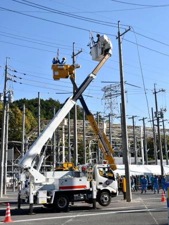 全国の一般送配電事業者の作業訓練で、切れた電線を仮復旧する作業員＝２０日午前、広島市