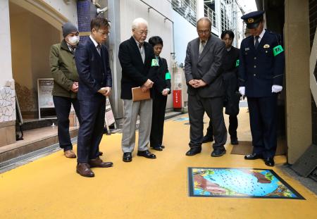 大阪市の繁華街「キタ」のラブホテル街で、黄色に塗装した道路に貼られたイラストを確認する大阪・曽根崎署員ら＝１０日午後、大阪市北区