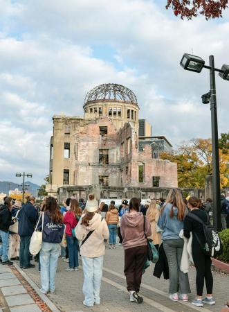 被団協へのノーベル平和賞授与から一夜明け、広島市の原爆ドームを訪れる外国人観光客ら＝１１日午前