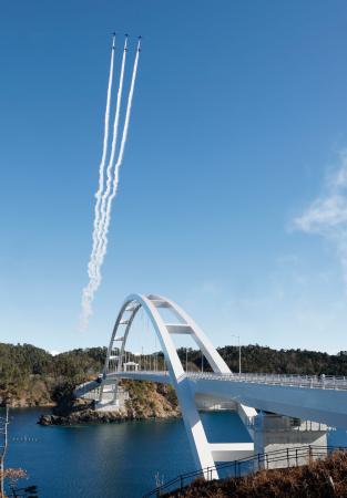 宮城県女川町で、「出島大橋」の開通を記念し上空を飛行するブルーインパルス＝１９日午後