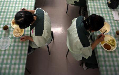 無言で昼食をかき込む女性受刑者たち＝２０１７年、岐阜県の笠松刑務所