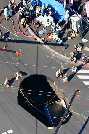 埼玉県八潮市の県道交差点で、陥没してできた穴に転落した車両＝２８日午前１１時５１分（共同通信社ヘリから）